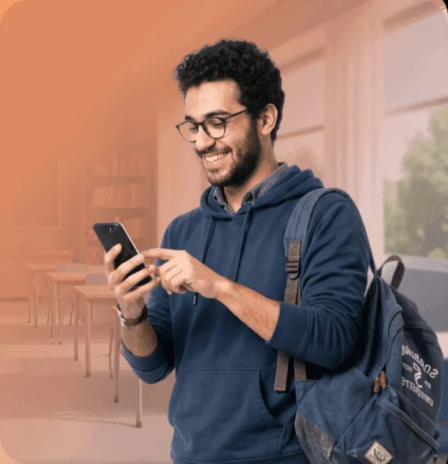 Smiling learner using their phone in a classroom